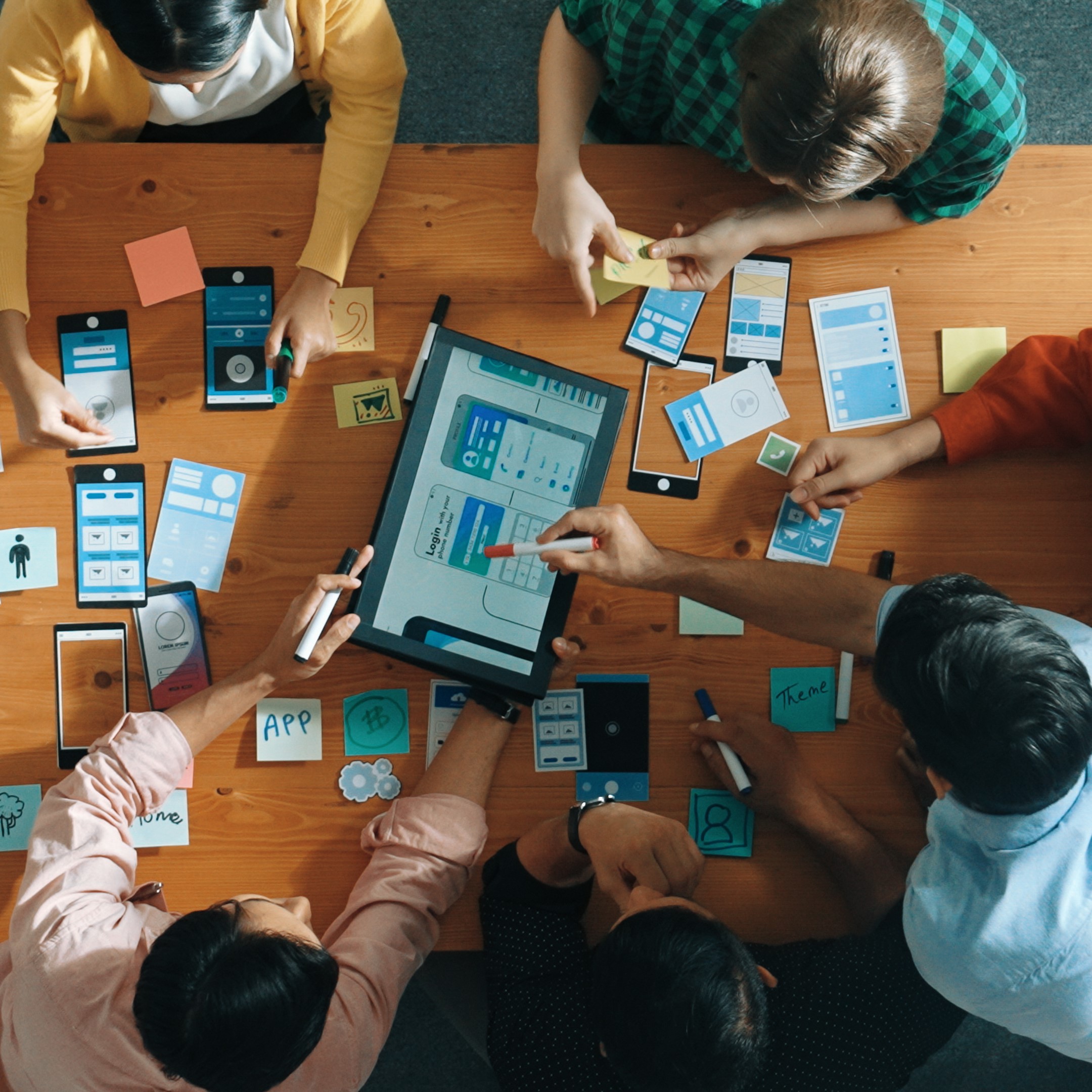 Product team arranging mobile wireframes and prototypes around a shared design workspace